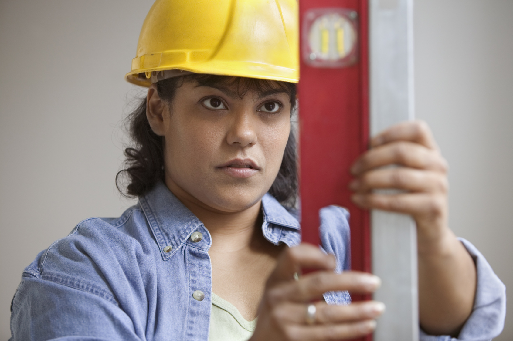Woman construction worker in hard hat reading level measurements
